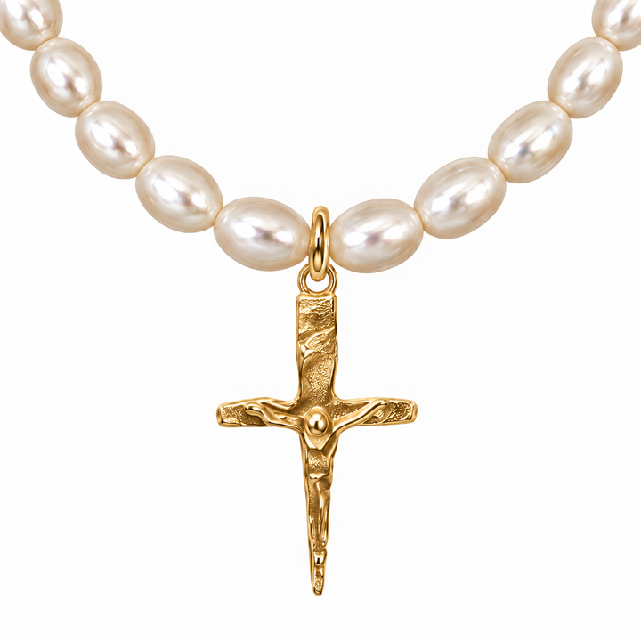 A close-up of a necklace featuring irregular white freshwater pearls and a textured gold crucifix pendant on a plain white background.