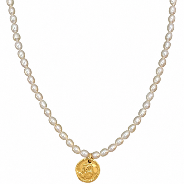 A strand necklace made of small white baroque pearls with a gold coin pendant featuring a rose engraving, shown against a plain white background.
