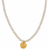 A strand necklace made of small white baroque pearls with a gold coin pendant featuring a rose engraving, shown against a plain white background.
