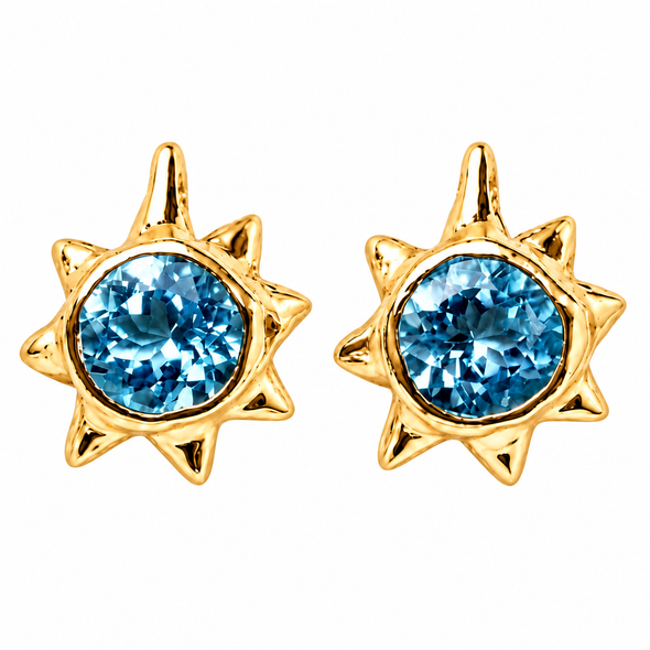 A pair of gold sunburst stud earrings featuring round-cut light blue gemstones, set against a plain white background.