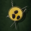 Three long silver skewers with barbed wire ends are arranged over a yellow drink in a clear glass, each threaded with a blackberry, on a dark green background.