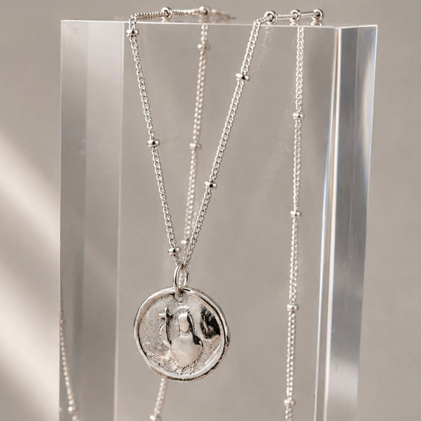 Necklace with a pendant on an acrylic stand against a neutral background