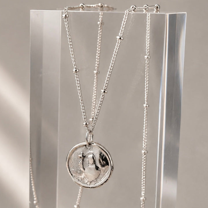 Necklace with a pendant on an acrylic stand against a neutral background