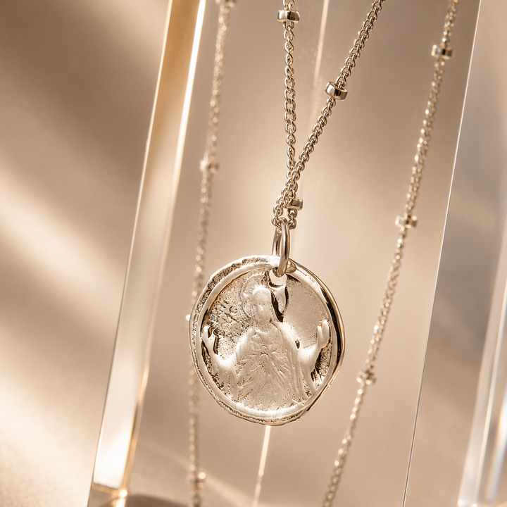 Silver necklace with a round pendant on a reflective surface