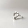 Silver ring with a circular design on a light gray background
