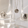 Silver jewelry including rings and a necklace on clear stands against a white background