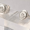 Silver rings with circular designs on a clear stand