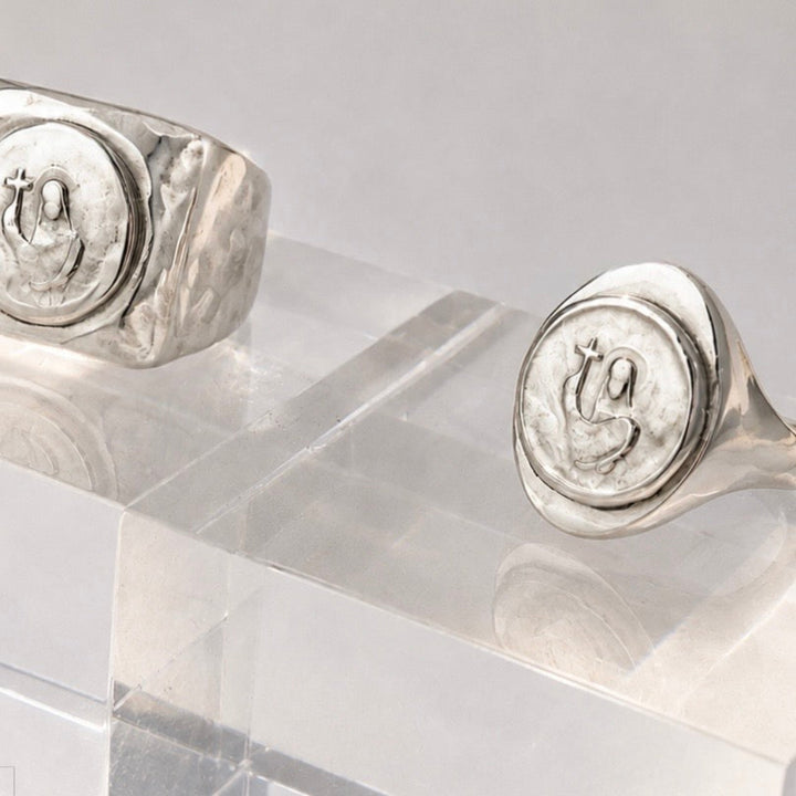 Silver rings with circular designs on a clear stand