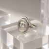 Silver ring with a circular design on a clear acrylic block