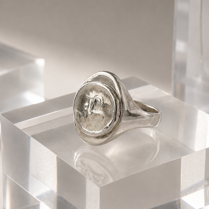 Silver ring with a circular design on a clear acrylic block