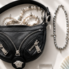 Collection of fashion items including a black handbag, jewelry, sunglasses, and a fan on a white surface.