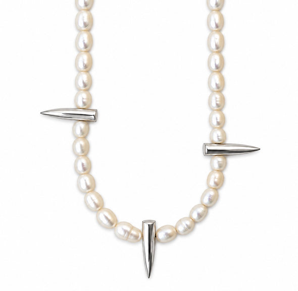 A pearl necklace with silver-toned spike accents, featuring a curved line of white pearls and three pointed metallic spikes, shown against a plain white background.