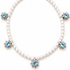 A pearl necklace with five light blue faceted gemstones set in silver starburst clusters, arranged in a circle on a white background.