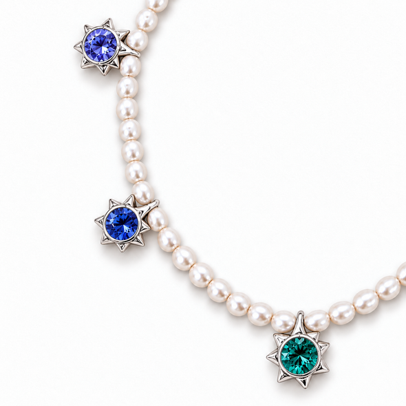 A pearl necklace with three star-shaped silver pendants, each set with a round gemstone in a different color: blue, emerald green, and deep purple, shown on a white background.