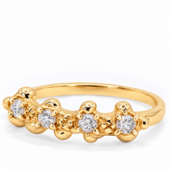A gold band ring featuring five round-cut clear gemstones in a flower-like cluster setting, photographed on a clean white background.