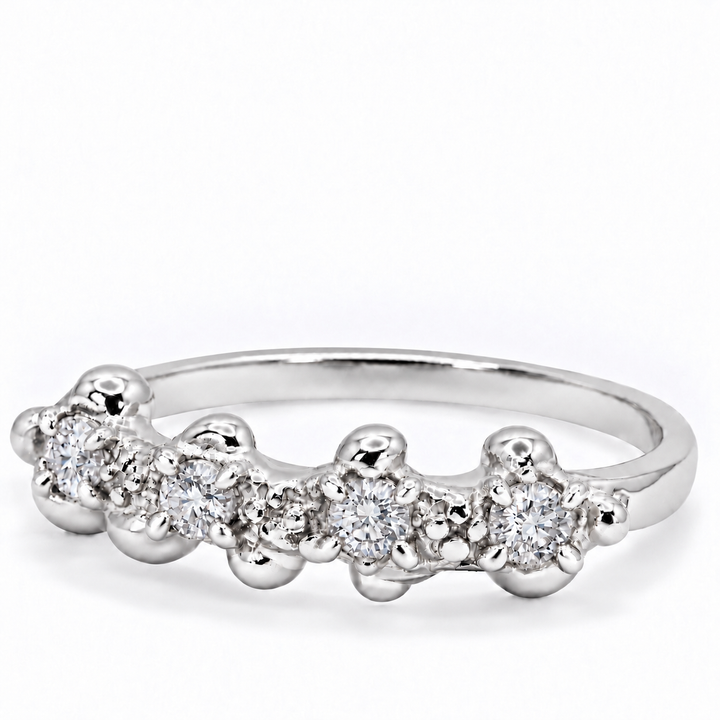 A silver band ring featuring a row of small clear gemstones in a beaded, flower-like setting, photographed on a clean white background.