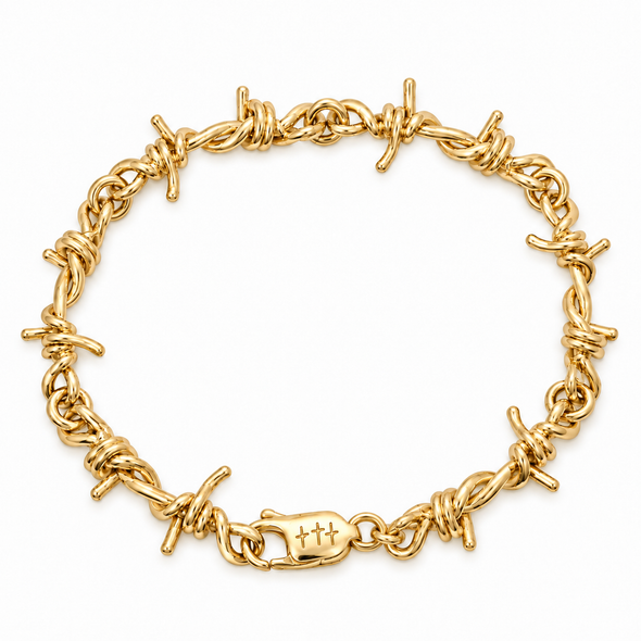 A yellow gold barbed wire bracelet with a matching lobster clasp engraved with three crosses, displayed on a clean white background.