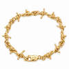 A yellow gold barbed wire bracelet with a matching lobster clasp engraved with three crosses, displayed on a clean white background.