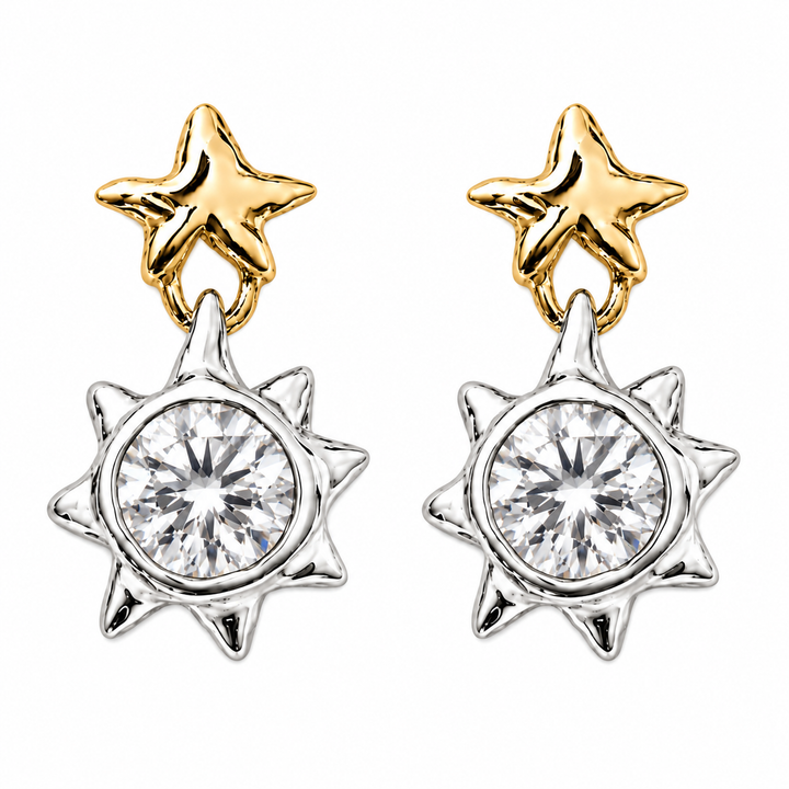 A pair of gold and silver dangle earrings, each featuring a polished gold star stud connected to a silver sunburst pendant with a clear round-cut center stone, shown on a plain white background.