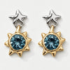 A pair of gold and silver dangle earrings featuring a central faceted blue gemstone in a spiky sunburst setting, with a textured silver star-shaped post above, shown on a light gray background.