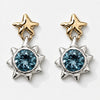 A pair of celestial dangle earrings featuring gold star-shaped studs and silver sunburst pendants with round blue gemstones, set against a clean white background.