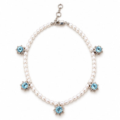 A pearl necklace with five star-shaped silver settings, each holding a light blue gemstone, displayed on a clean white background.
