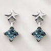 A pair of silver star dangle earrings with faceted light blue gemstones, displayed on a clean white background.