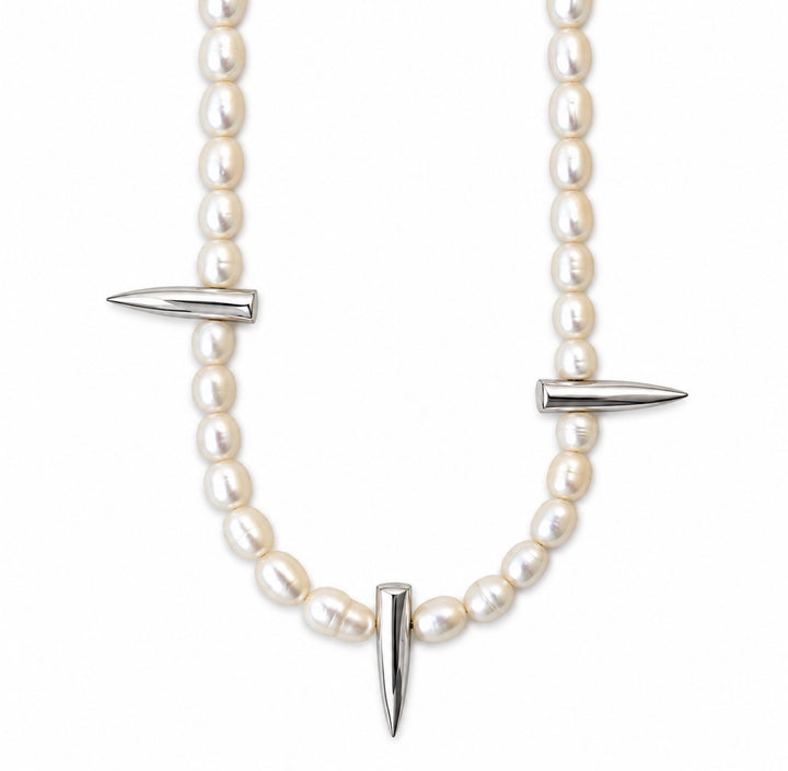 A double-strand pearl necklace with silver-toned spike accents, featuring a curved line of white pearls and three pointed metallic spikes, shown against a plain white background.
