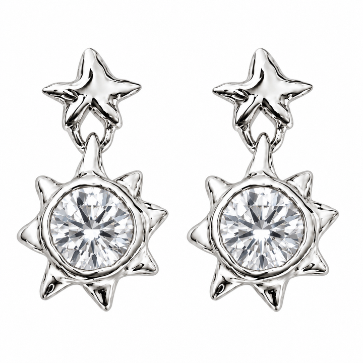 A pair of silver-toned dangle earrings featuring a five-pointed star at the top and a larger multi-pointed starburst shape below, each holding a clear faceted round gemstone, shown on a plain white background.