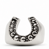 A silver horseshoe-shaped ring with a textured, dark oxidized pattern along the top curve, set against a plain white background.