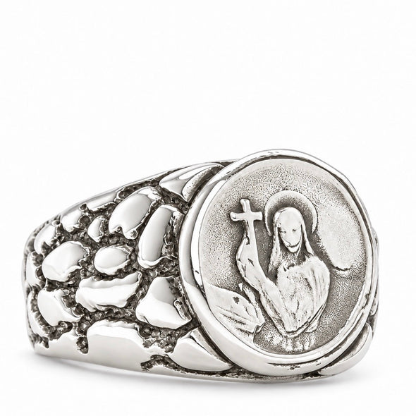 A silver signet ring featuring a circular medallion with an embossed figure holding a cross, set against a textured, stone-like band on a clean white background.