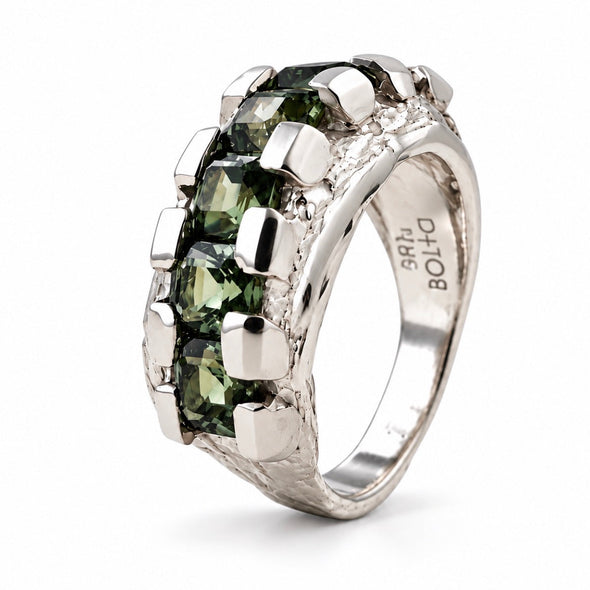 A silver ring featuring a row of green rectangular gemstones in a prong setting, with a textured silver band. The inside of the band is engraved with 