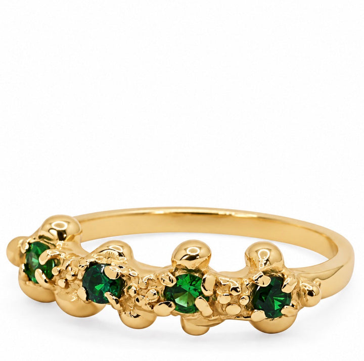 A gold ring featuring a row of green gemstones in a textured, clustered setting, photographed on a clean white background.