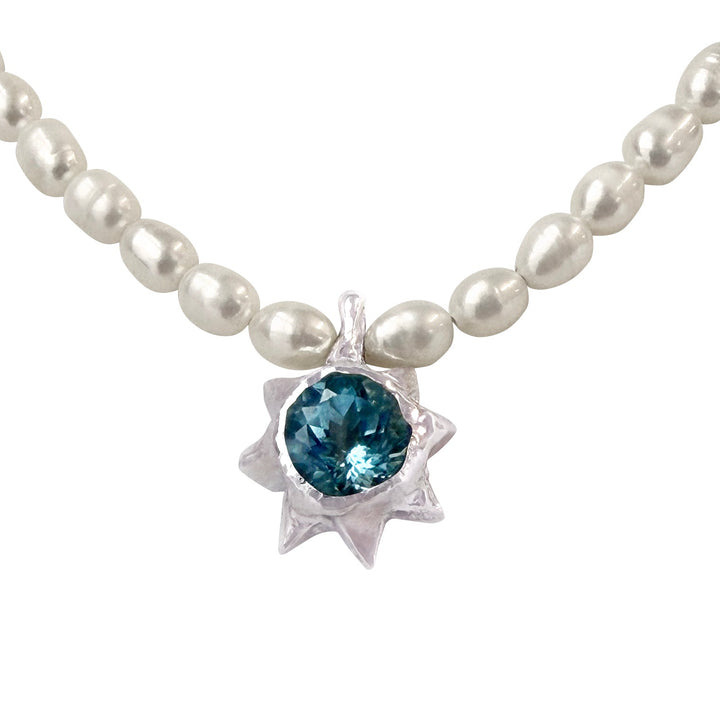 Pearl necklace with a blue gemstone pendant on a white background