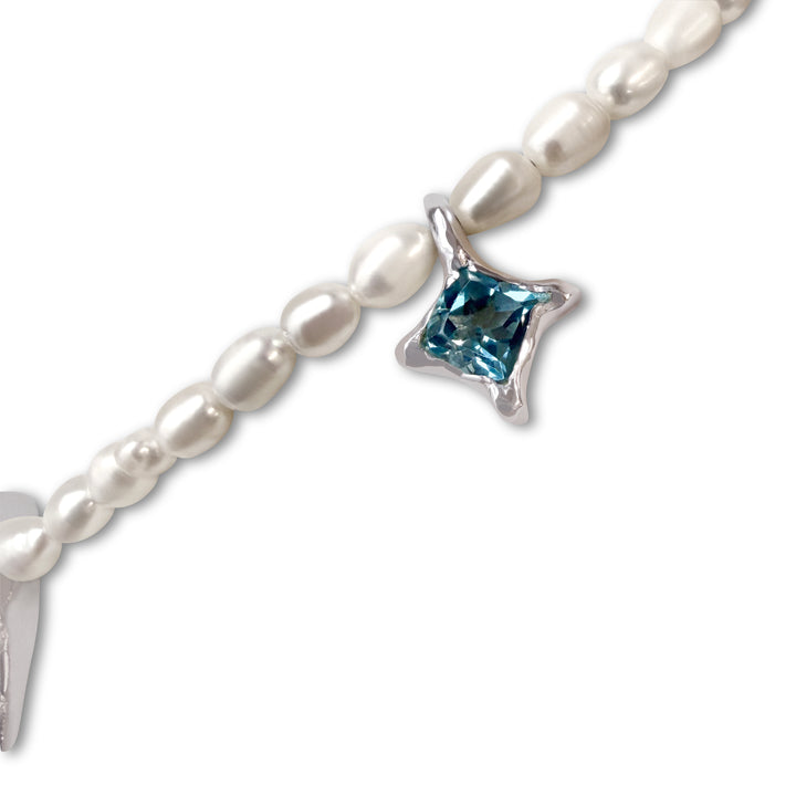 Pearl bracelet with a blue gemstone charm on a white background