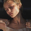 Woman with closed eyes wearing jewelry against a dark background