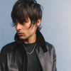 Person wearing a black leather jacket against a blue background