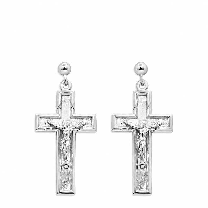 A pair of silver crucifix dangle earrings with a textured cross design featuring a detailed corpus, suspended from round silver studs on a plain white background.
