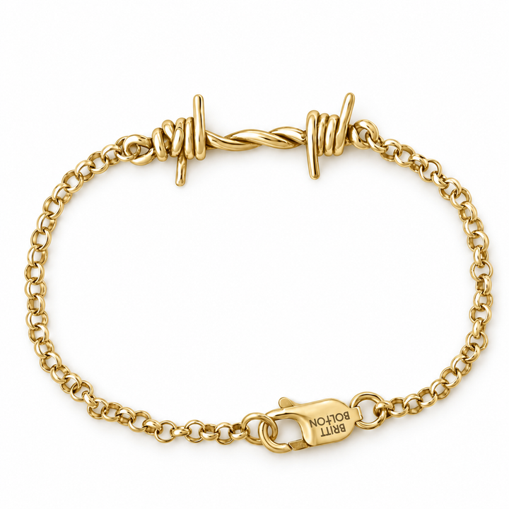 A gold chain bracelet with twisted barbed wire details at the top and a lobster clasp engraved with 'BRITT BOLTON', shown on a plain white background.