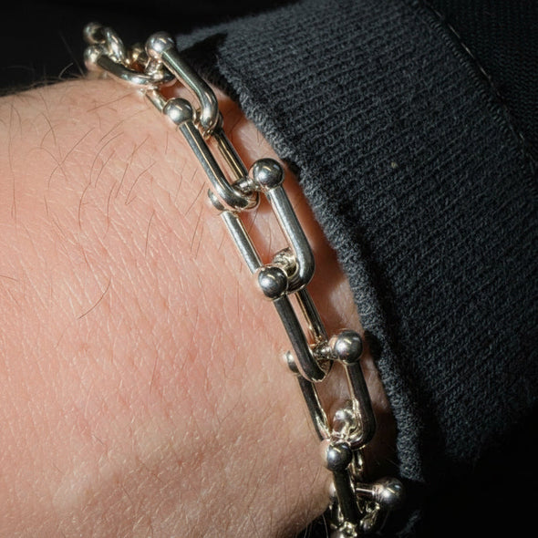 Silver chain bracelet on a wrist with a dark sleeve