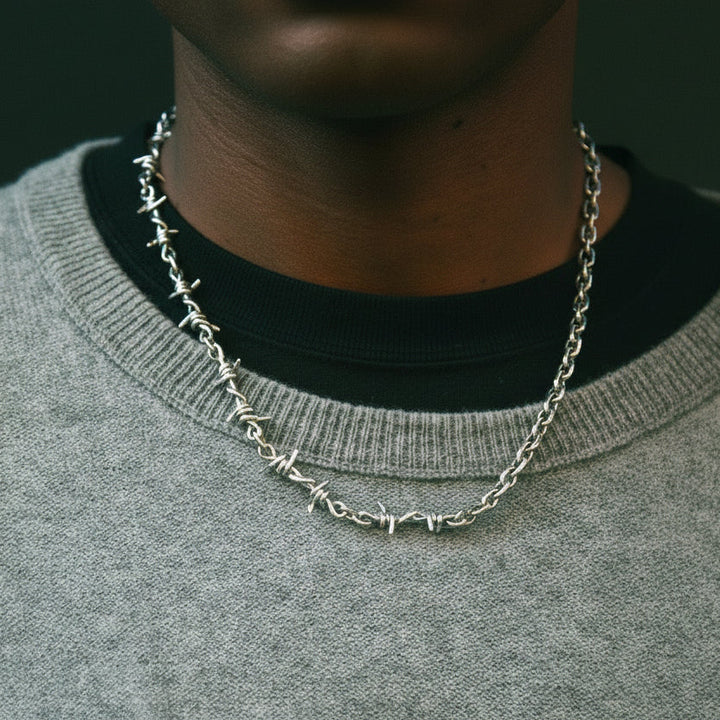 Person wearing a silver chain necklace with a dark background