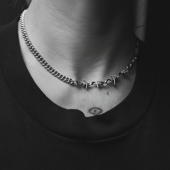 Necklace with barbed wire design worn by a person against a black background
