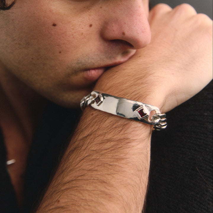 Man wearing a silver bracelet with a dark background