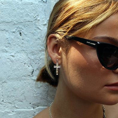 Woman wearing black sunglasses with a white brick wall background