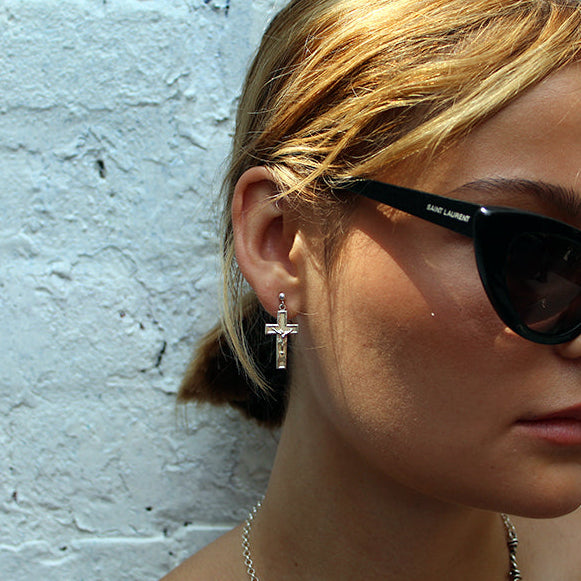 Woman wearing black sunglasses with a white brick wall background