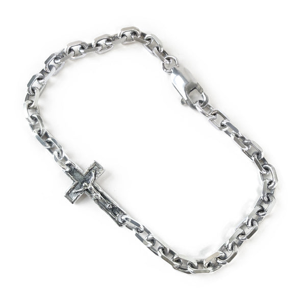 Silver chain bracelet with a cross pendant on a white background