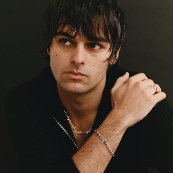 Man wearing a black jacket with jewelry on a dark background
