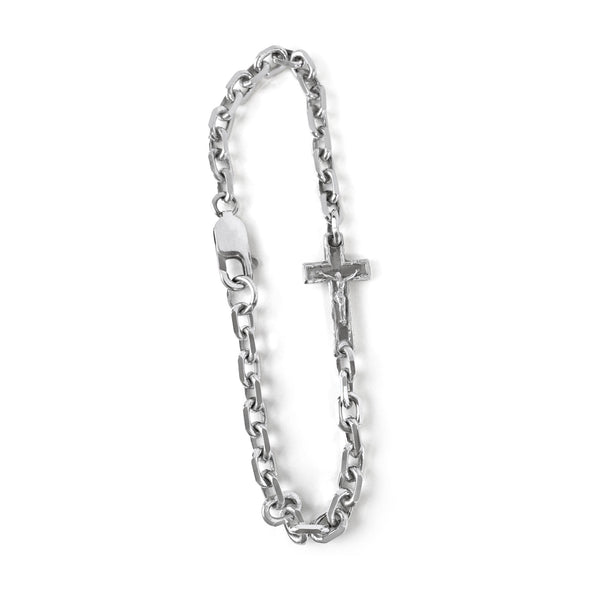 Silver chain bracelet with a cross charm on a white background