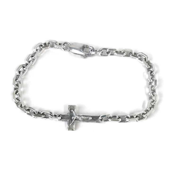 Silver chain bracelet with a cross charm on a white background
