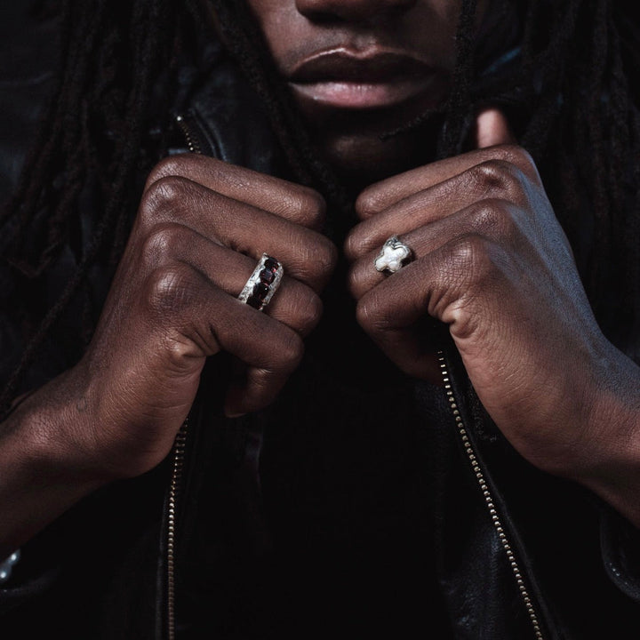 Close-up of a person wearing two rings on a dark background